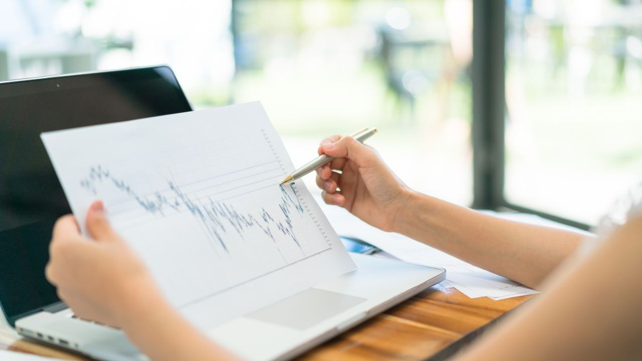 Piyasa &ccedil;arpanları ile yapılan analizi elinde kağıt tutarak inceleyen kişi